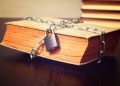 old book wrapped with chain and locked on padlock on table, concept, toned