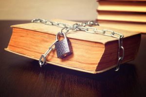 old book wrapped with chain and locked on padlock on table, concept, toned